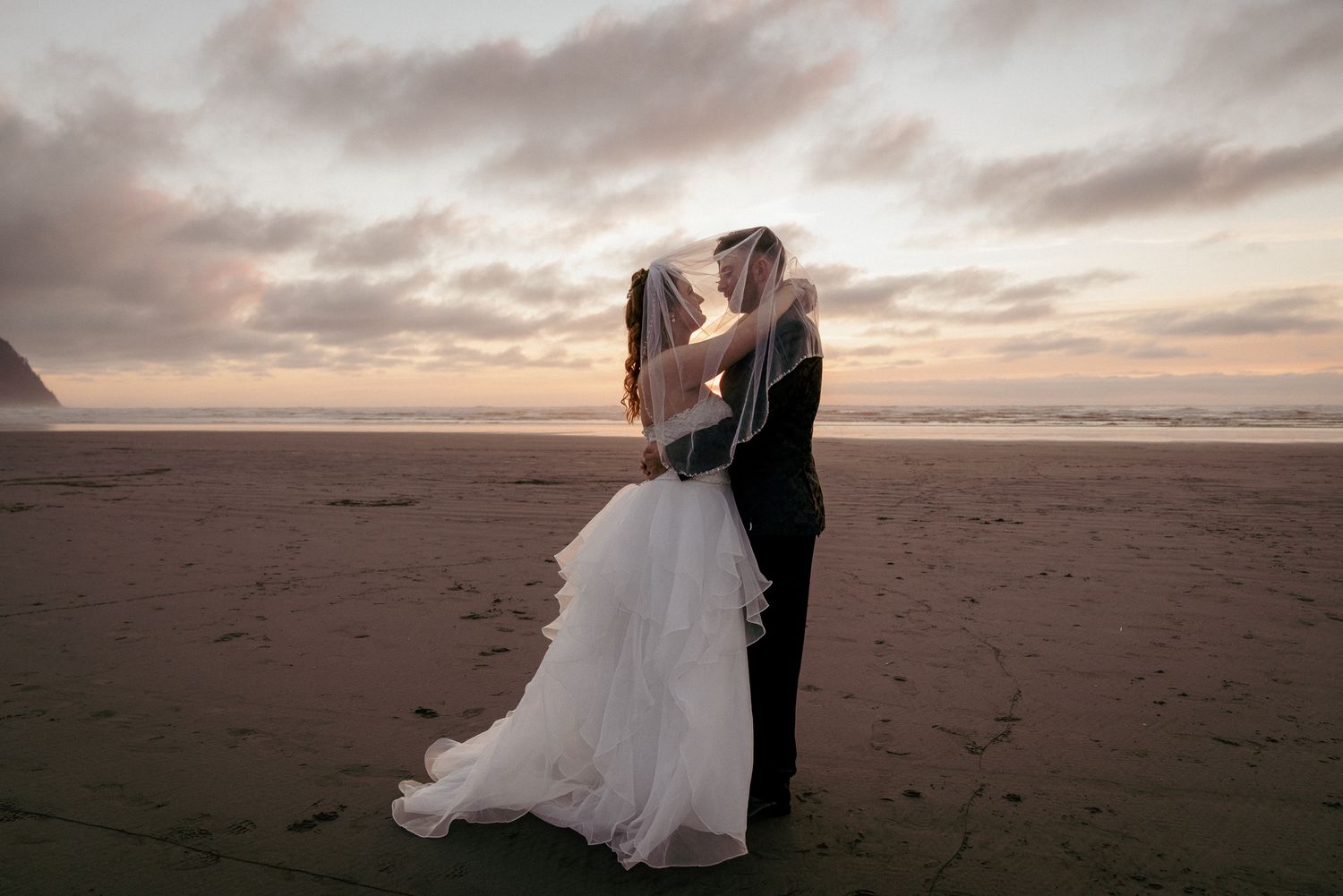 Bride and groom kisses at sunset on Oregon beach, romantic elopement.