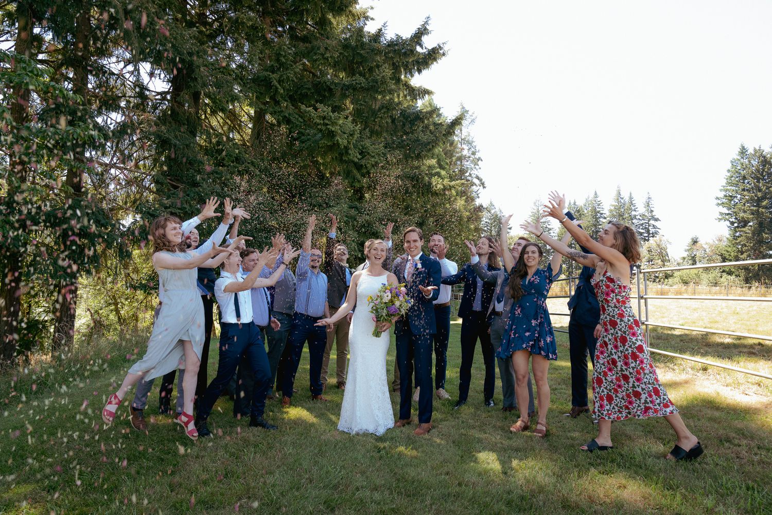 Wedding party cheers for newlyweds, outdoor summer ceremony in Oregon.