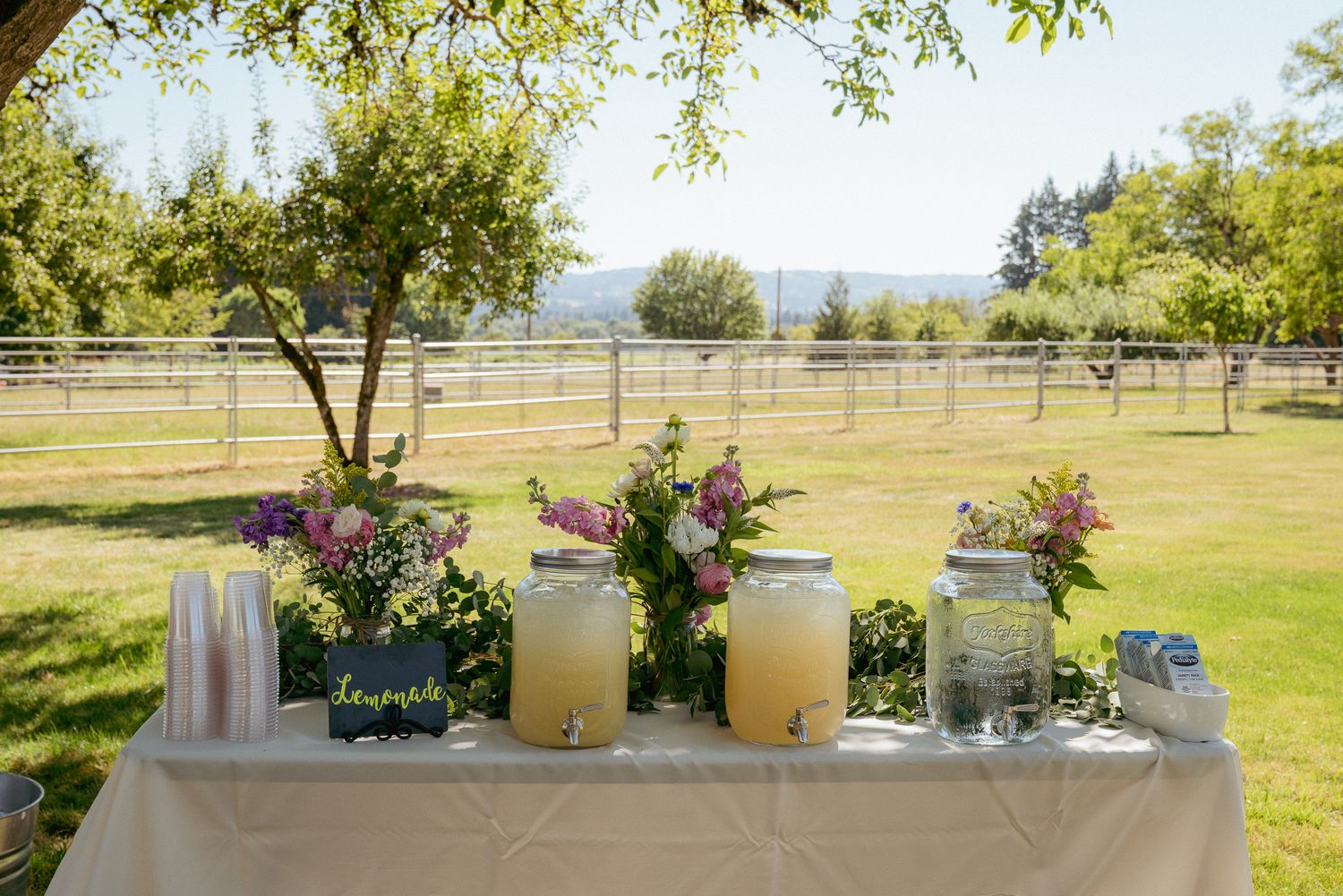 Farm wedding drink bar with florals and lemonade, rustic PNW charm.