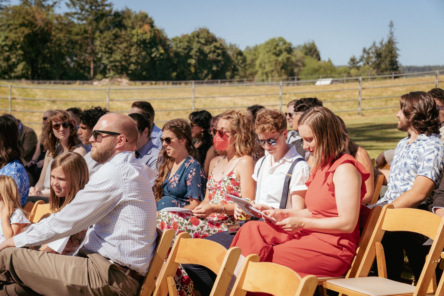 Guests smile during sunny Oregon ceremony, outdoor summer wedding.