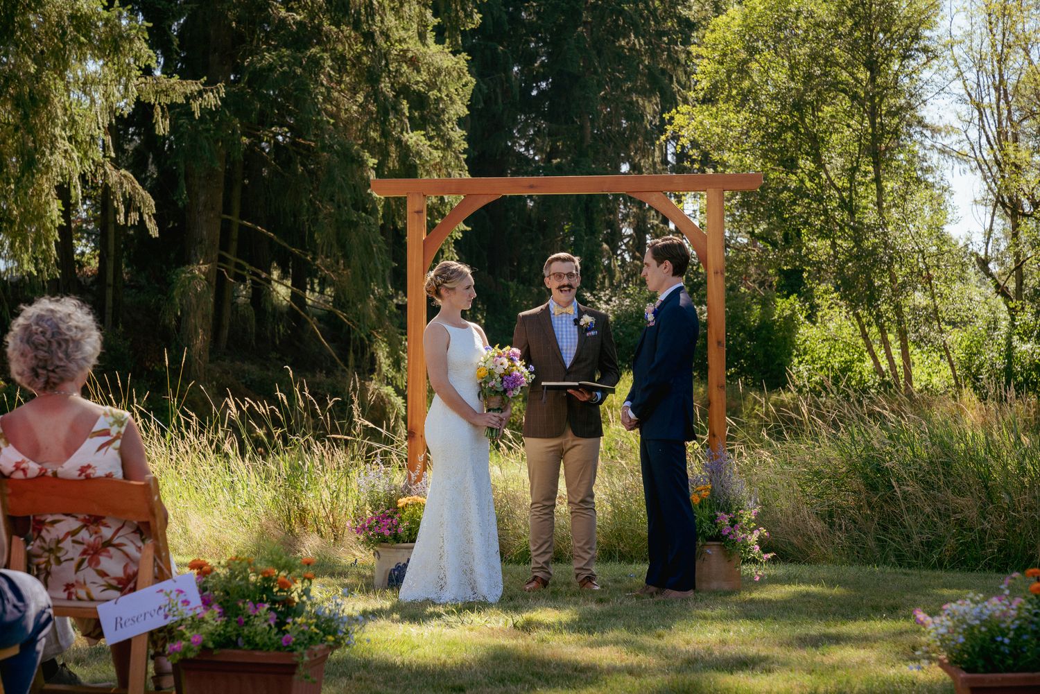 Bride and Groom exchanges vows under arbor, intimate forest elopement.