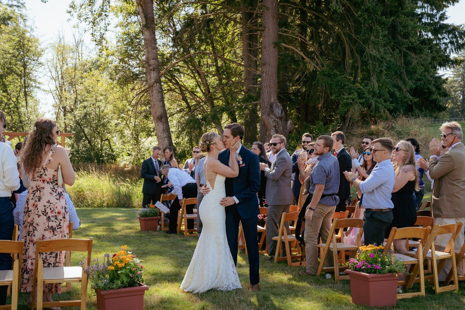 Outdoor wedding ceremony in Oregon woods. Guests seated as bride walks down the aisle.