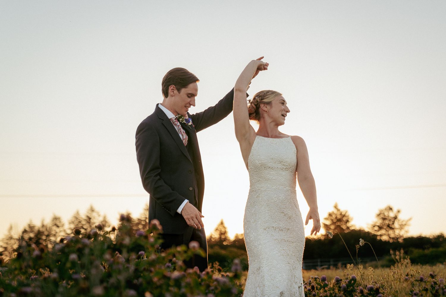 Groom spins bride during sunset, romantic PNW vineyard wedding.