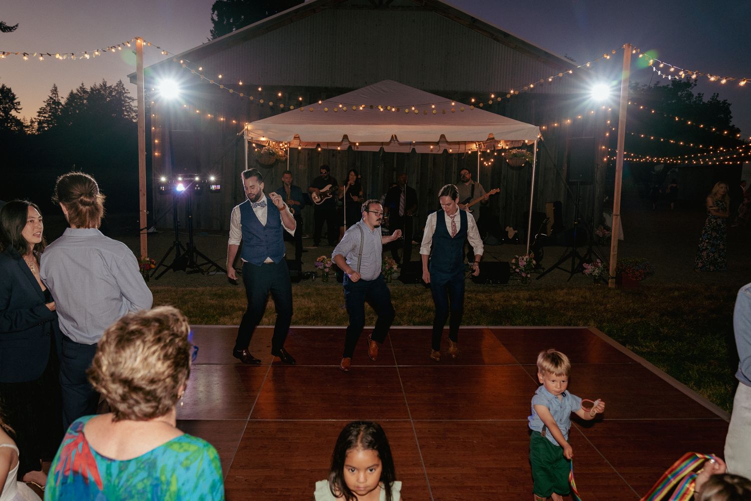 Guests dancing under tent with string lights, PNW night wedding.