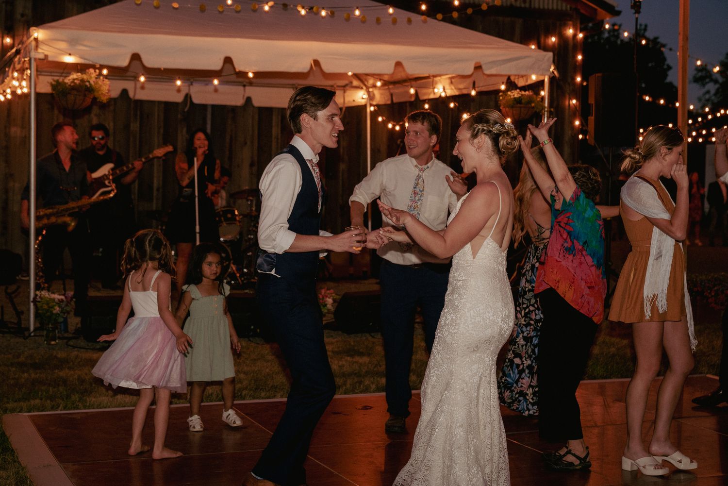 Bride and groom dance under string lights, rustic Portland reception.