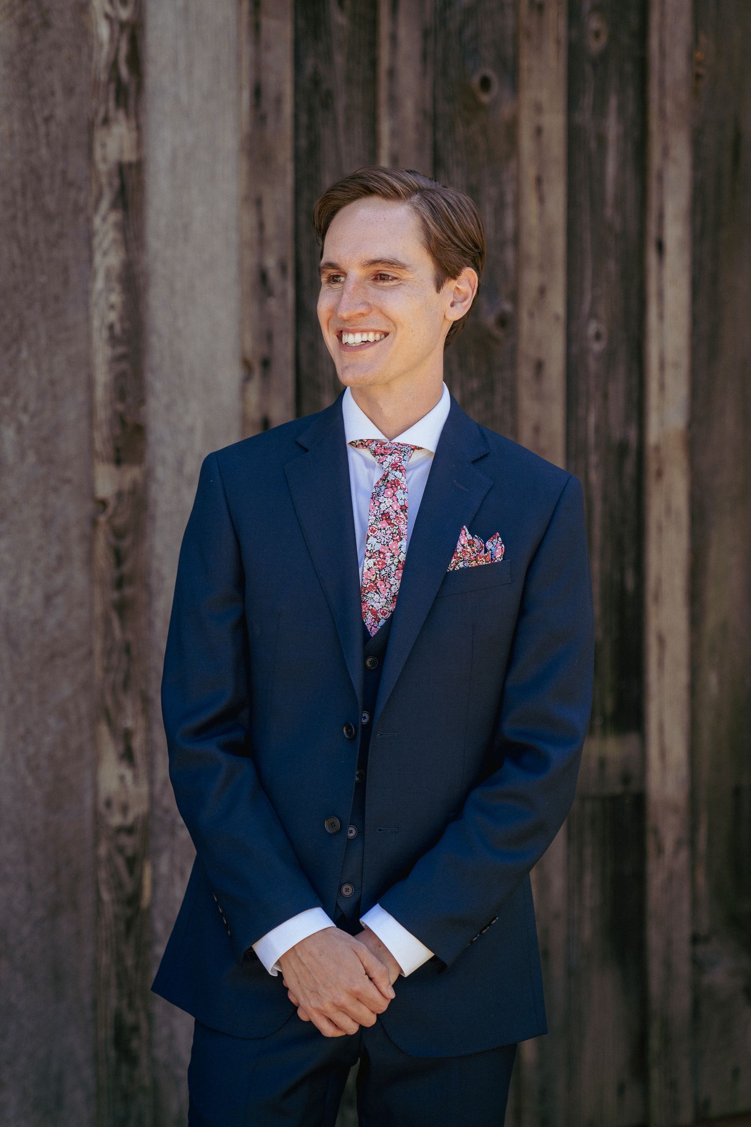 Groom smiling in blue suit, rustic PNW venue first look moment.