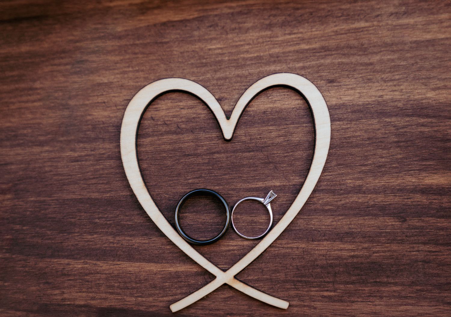Wedding rings arranged in heart shape with ribbon, romantic flat lay.