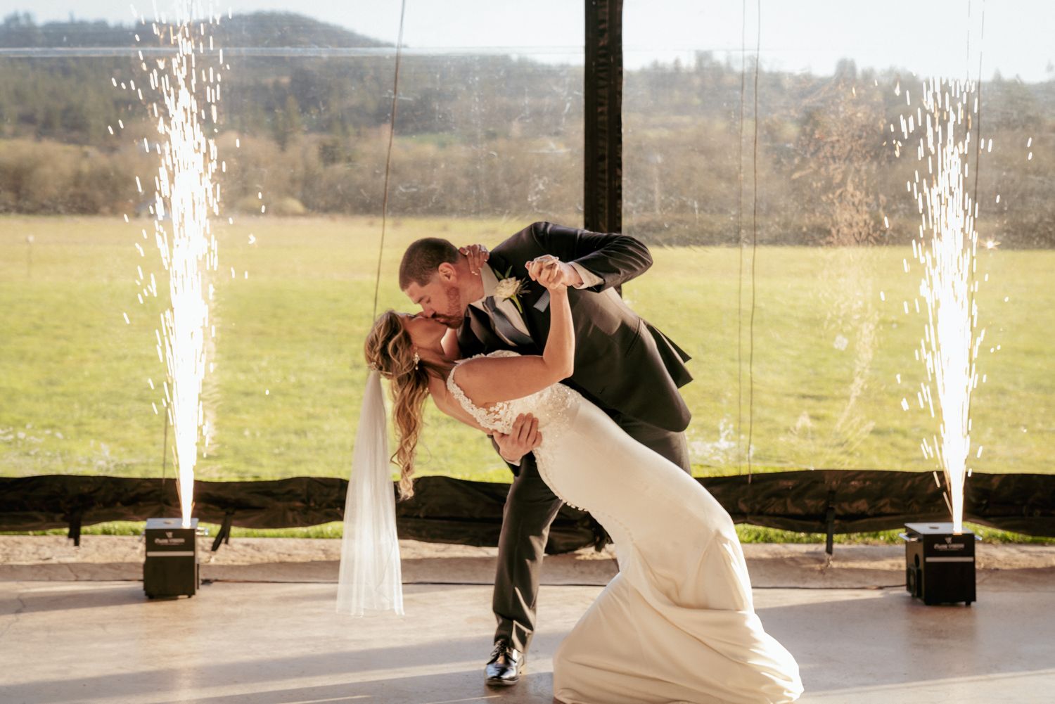 Newlyweds share dramatic dip kiss indoors, Oregon vineyard venue.