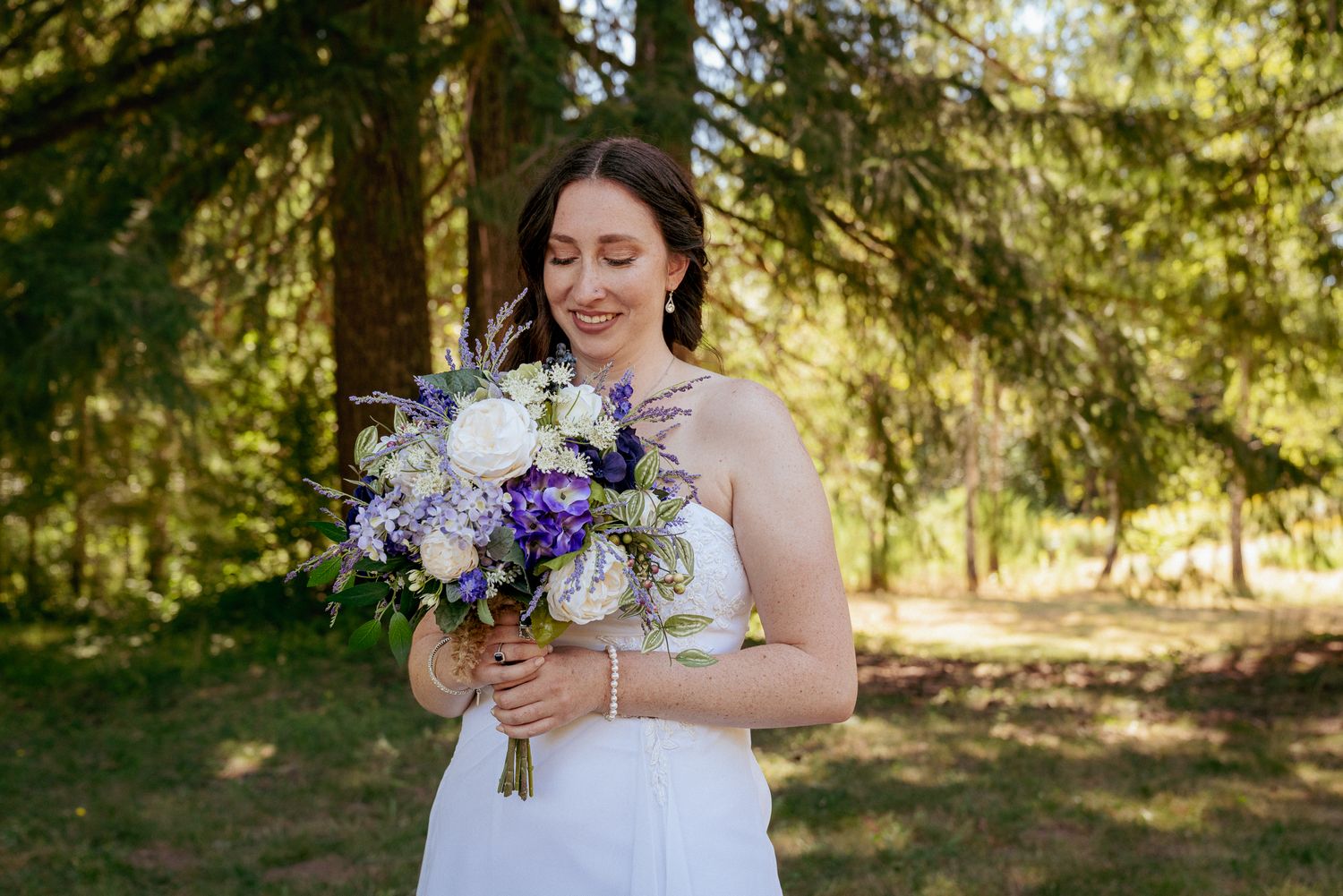 Bride holding purple and white bouquet, forest elopement near PDX.