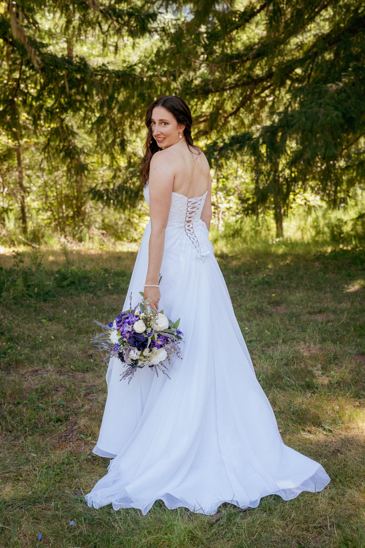 Bride in flowy gown with wildflowers, Central Oregon forest elopement.