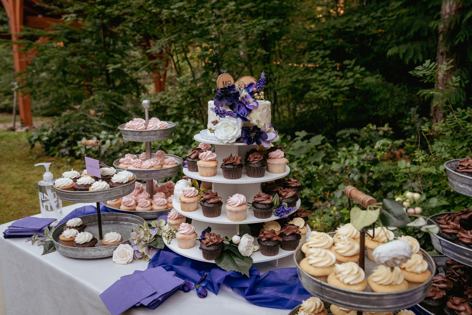 Tiered dessert display with cupcakes and macarons, whimsical forest wedding treats.
