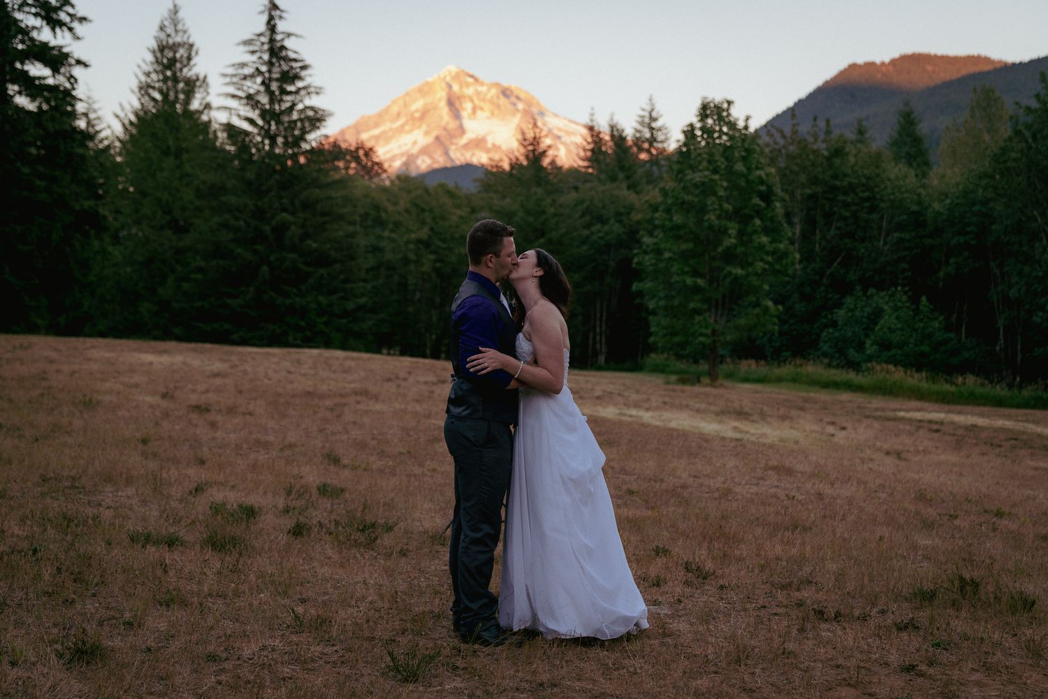 Couple kisses at golden hour in front of Mt. Hood, classic Oregon wedding.