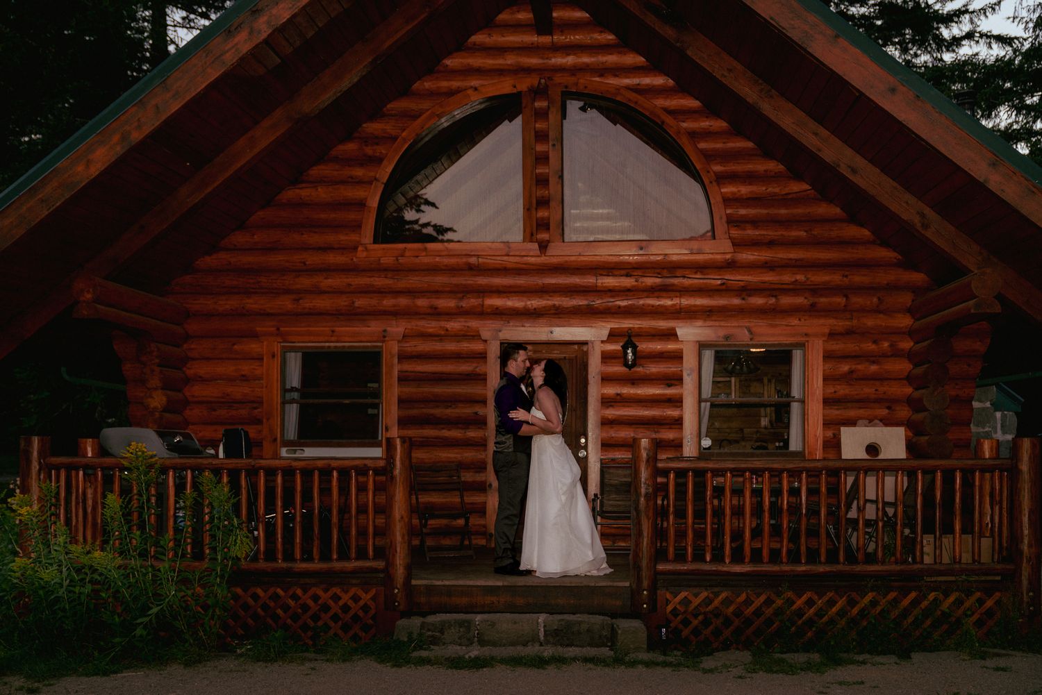 Bride and groom hug in front of log cabin, rustic Oregon elopement.