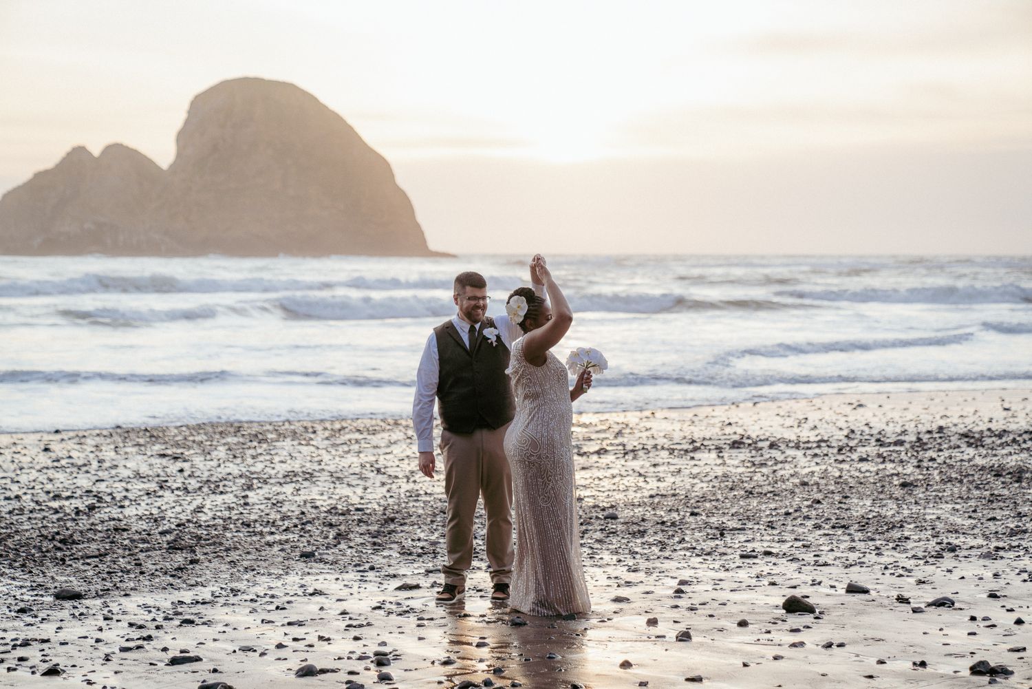 Interracial couple dancing at Oregon Coast, barefoot beach elopement. Pacific ocean behind them.
