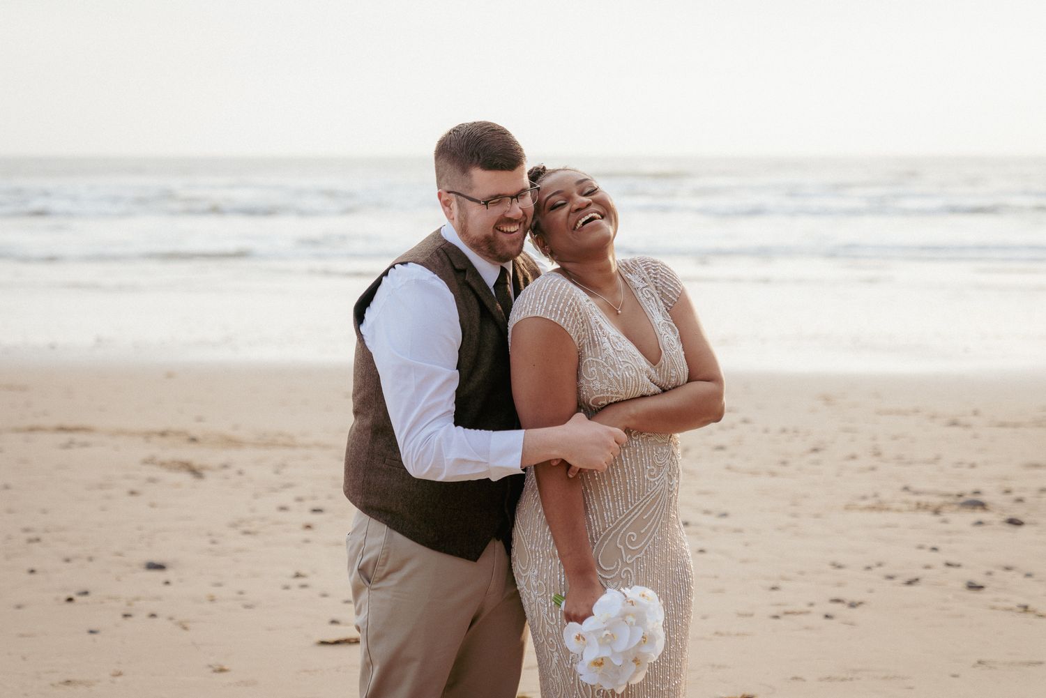 Interracial couple embraces on Oregon Coast, joyful beach elopement.