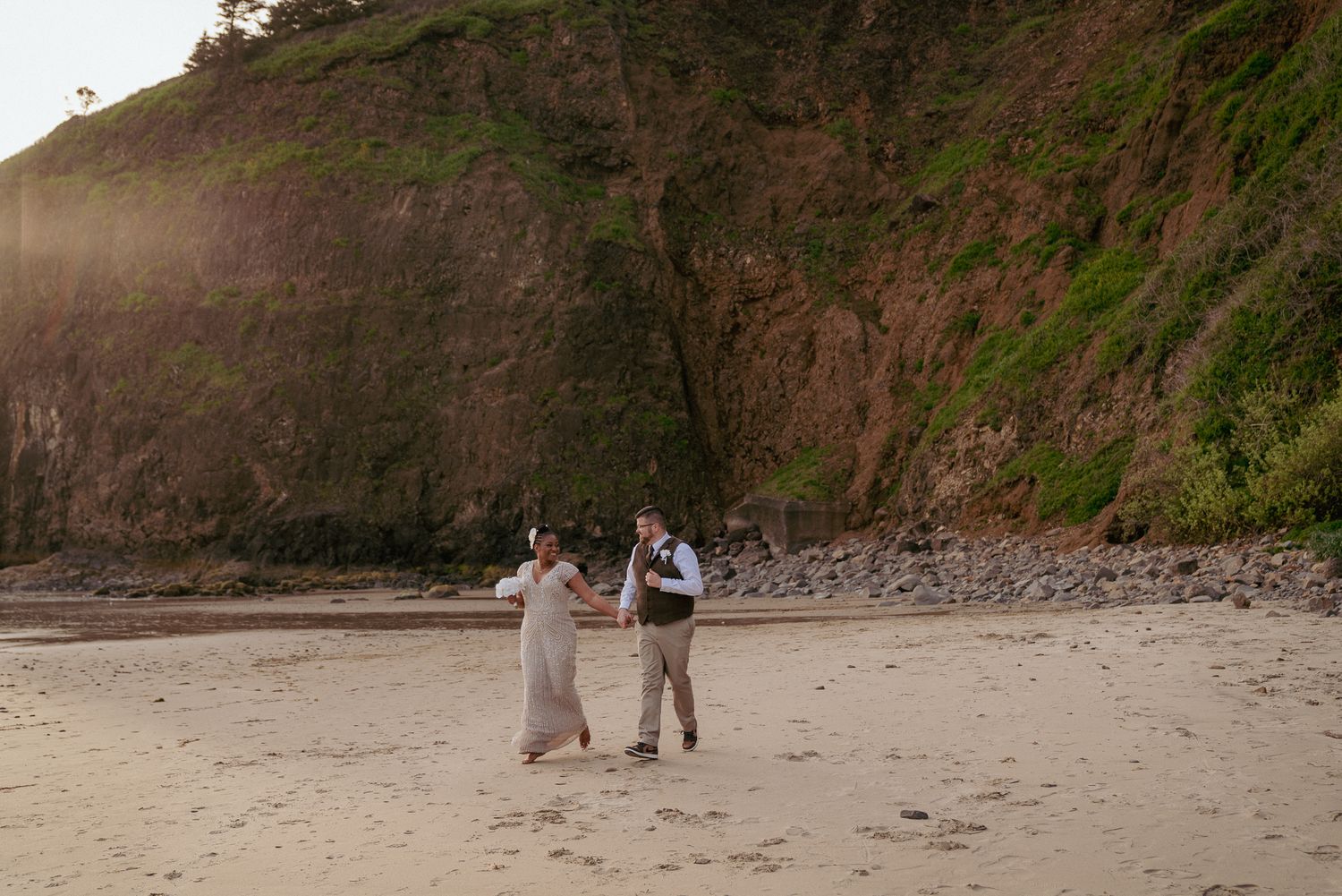 Bride and groom walk barefoot on Oregon beach, elopement wedding.