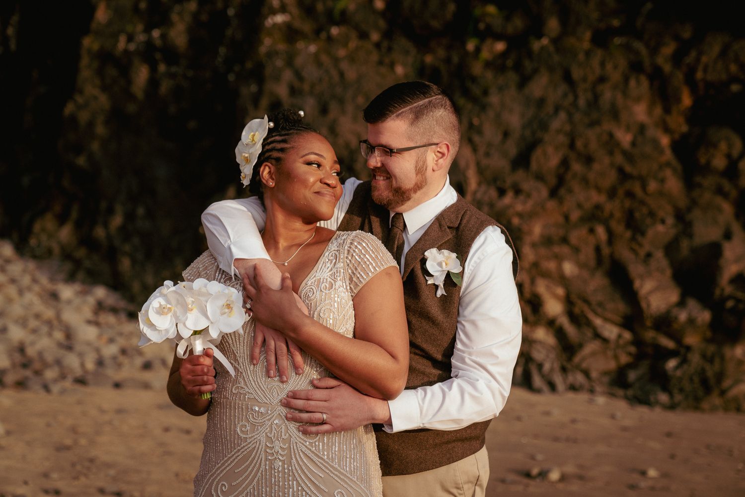 Black bride and white groom embrace after beach ceremony, PNW love.