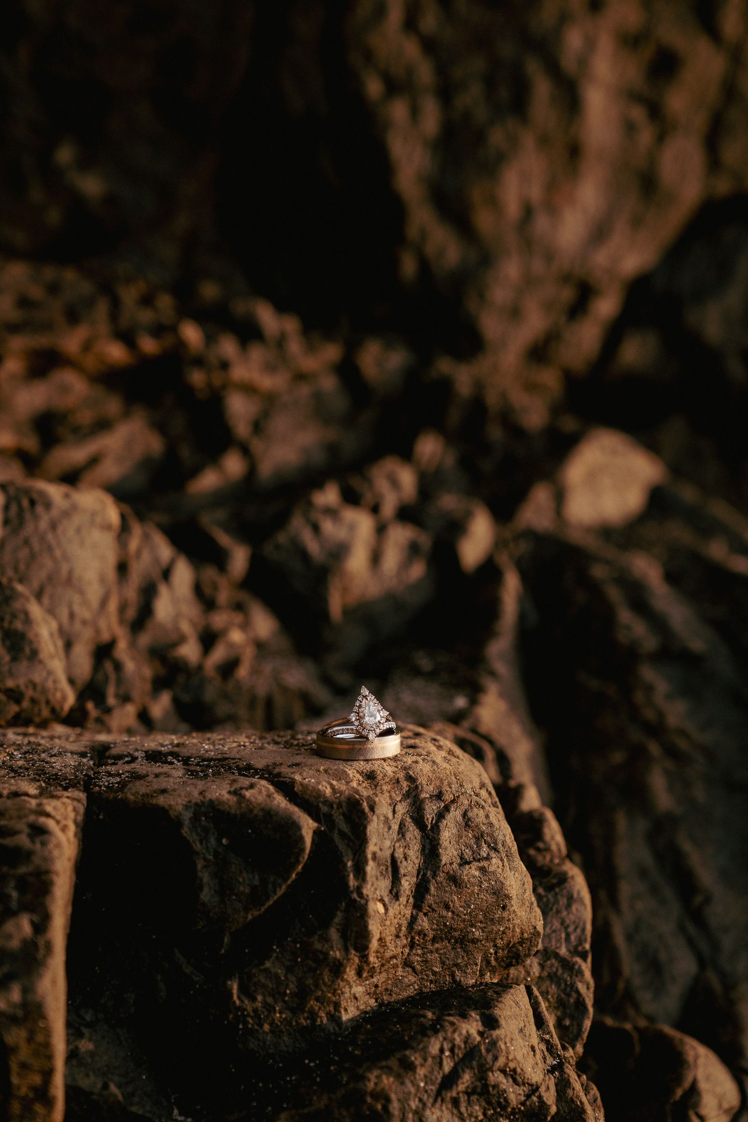 Engagement ring on rugged rocks, earthy PNW love story detail.
