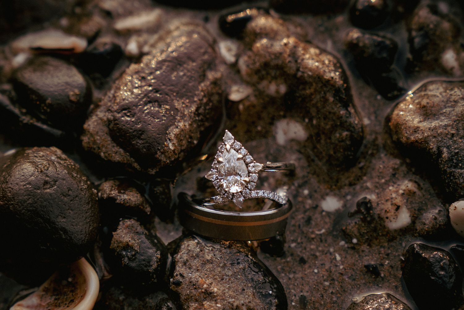 Diamond rings on wet rocks, earthy and romantic PNW engagement shot.