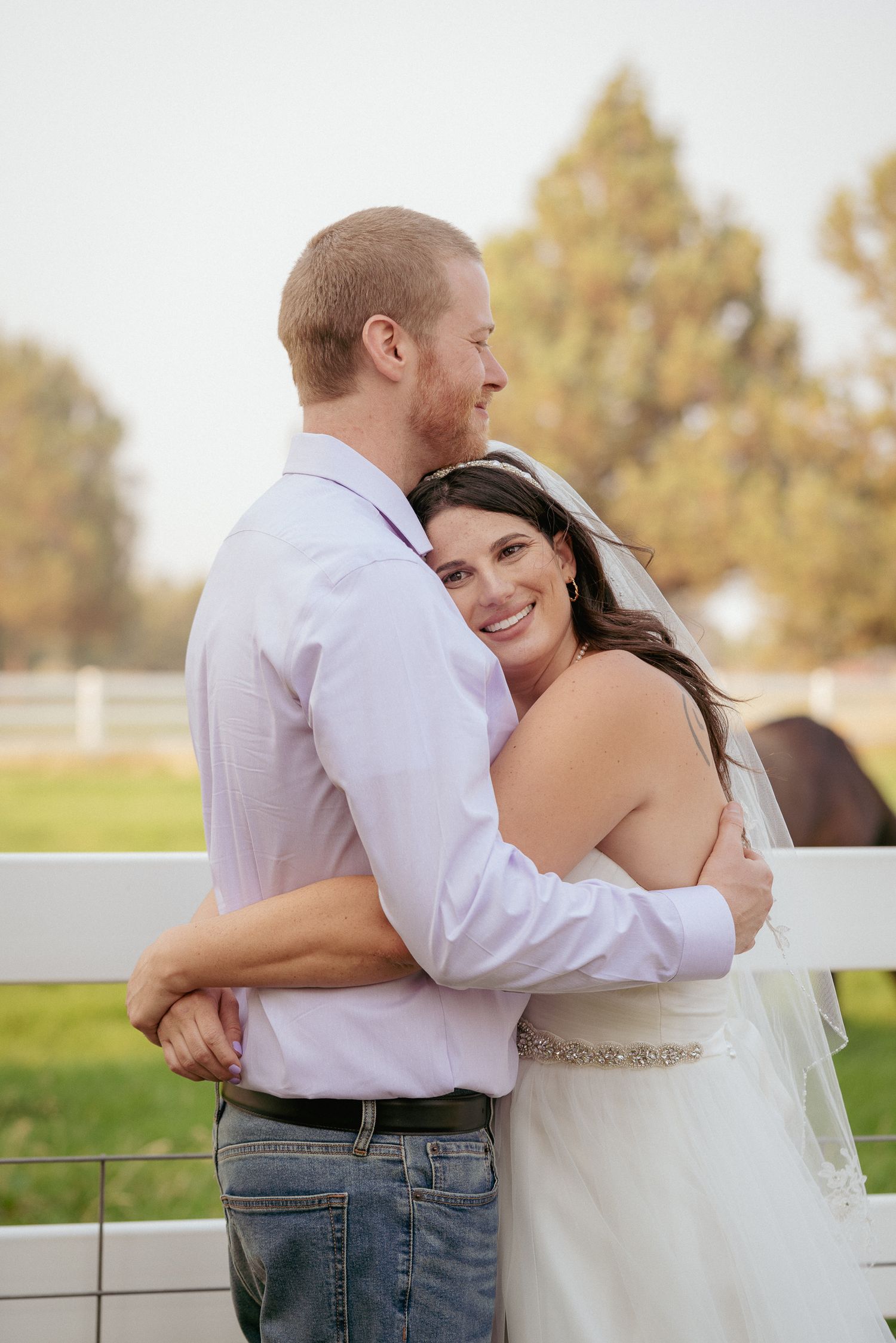 Mixed-race couple cuddle during golden hour in Oregon vineyard.