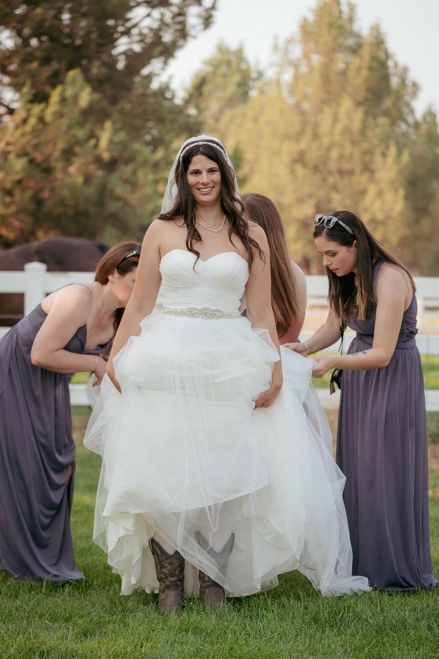 Bride laughs as bridesmaids fluff dress, candid PNW wedding prep.