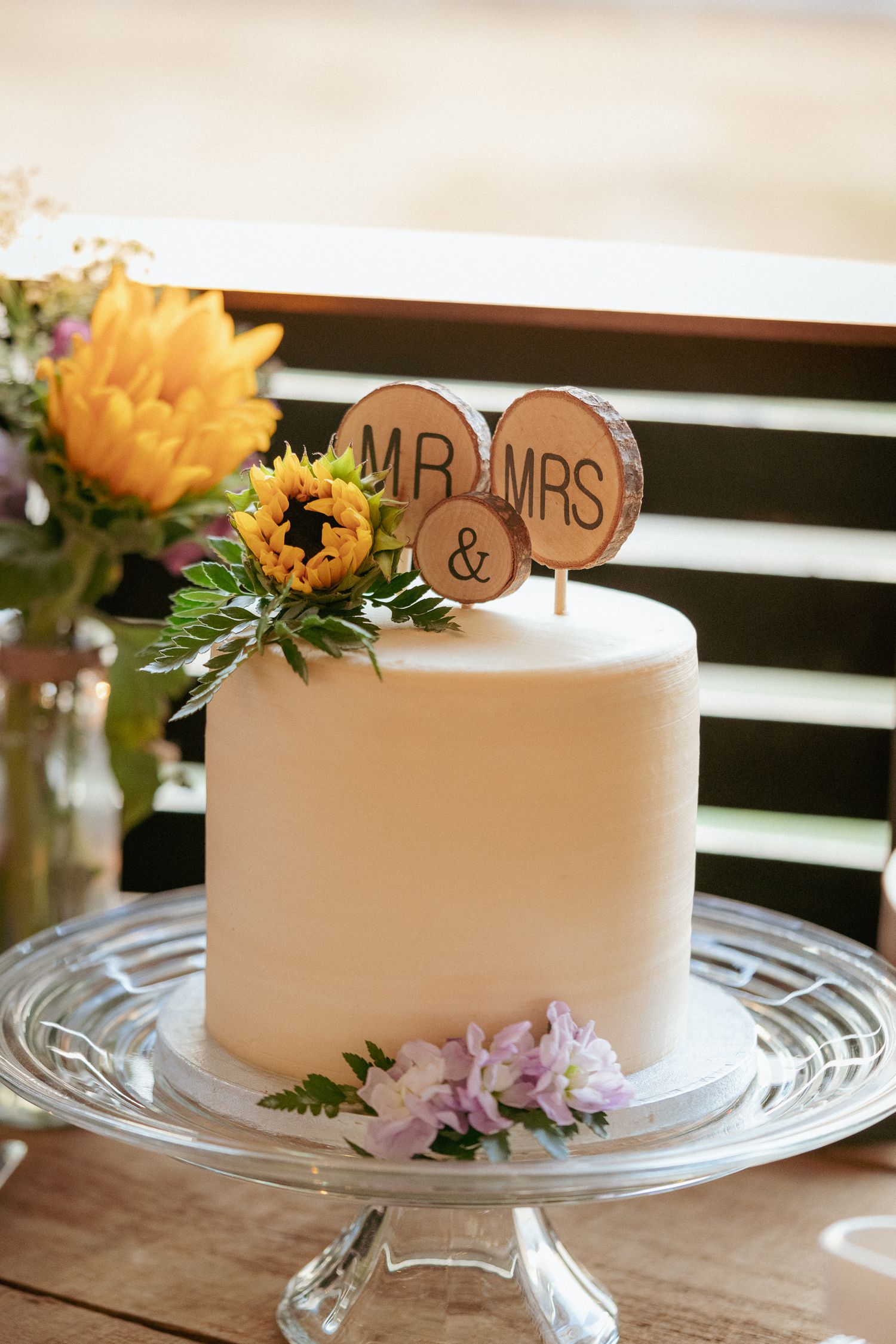 Simple white wedding cake with sunflower topper, Portland backyard.