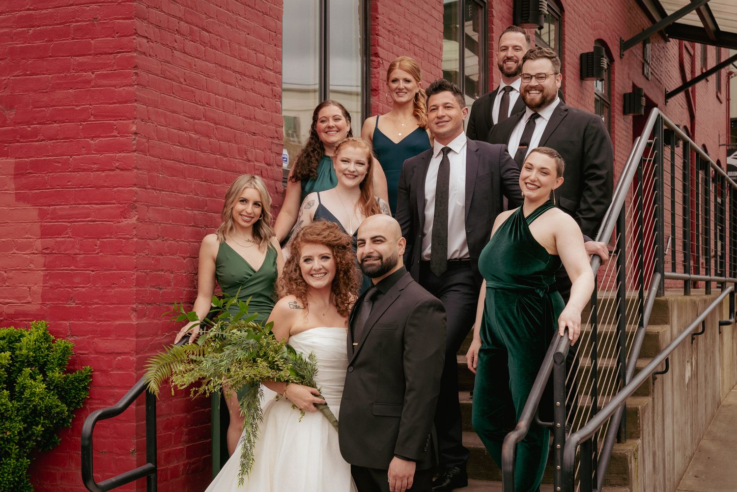 Bride, groom, and bridal party standing in front of red brick building Portland Downtown. Fun and formal group shot.