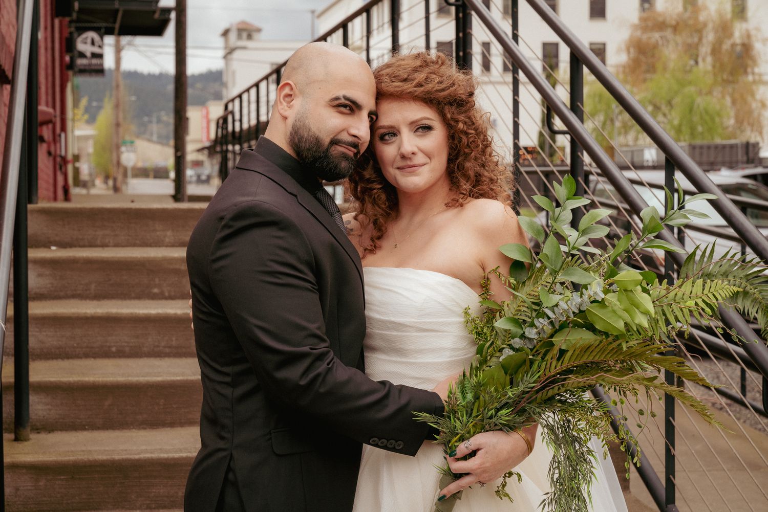 Interracial couple pose on elegant stone stairs, Portland Downtown venue.
