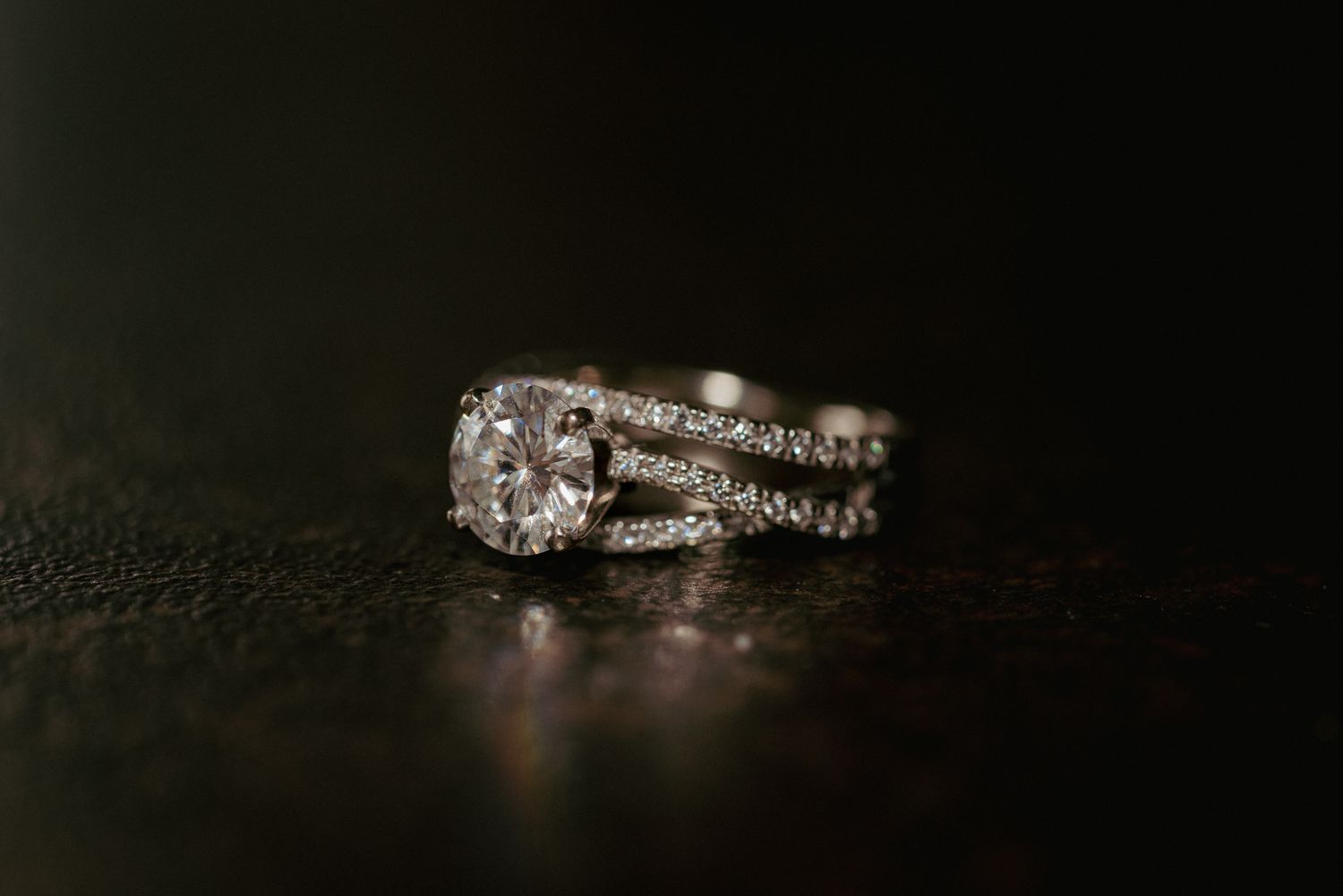 Diamond wedding ring set on dark wood, elegant PNW detail shot.