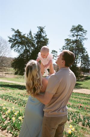 A family shares a tender moment together outdoors in a spring garden filled with blooming daffodils on a sunny day.