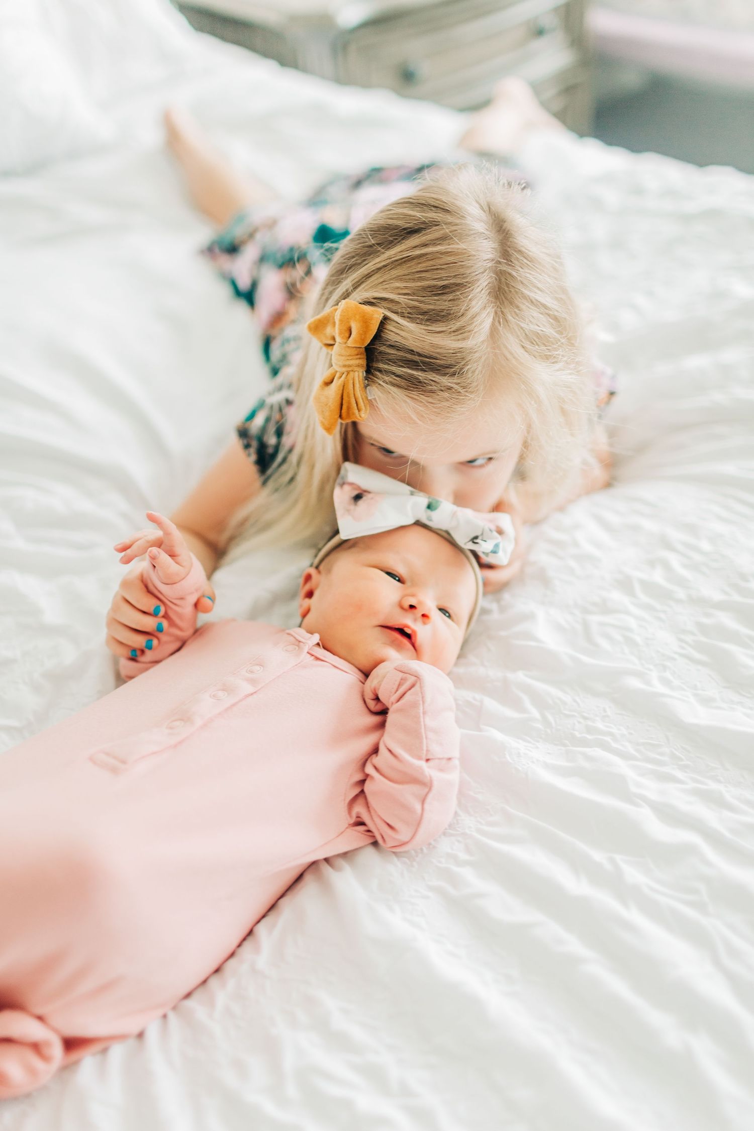 Big sister kissing little baby sister on the bed