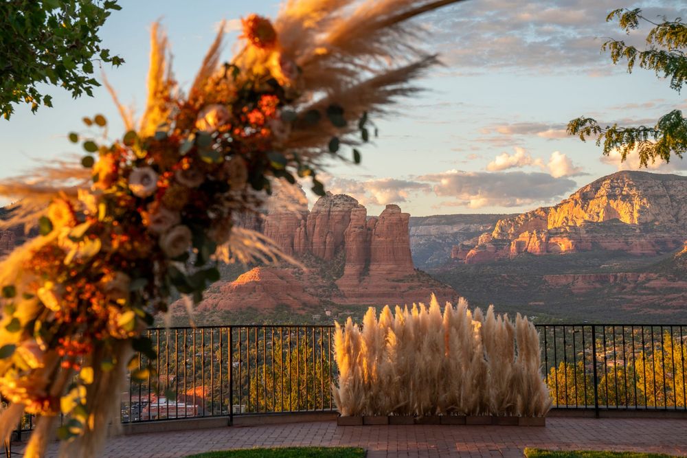 Sedona red rock canyon sunset view from a decorated terrace with pampas grass and floral arch in warm golden light.