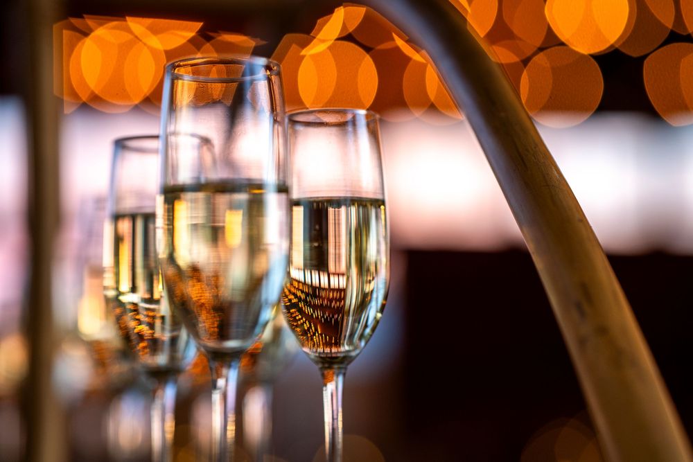 Elegant champagne flutes filled with sparkling wine against a warm bokeh light background at a festive celebration.
