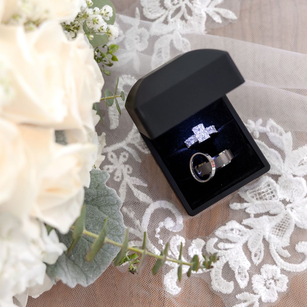 Wedding ring box with engagement ring and wedding band on lace fabric with eucalyptus leaves.