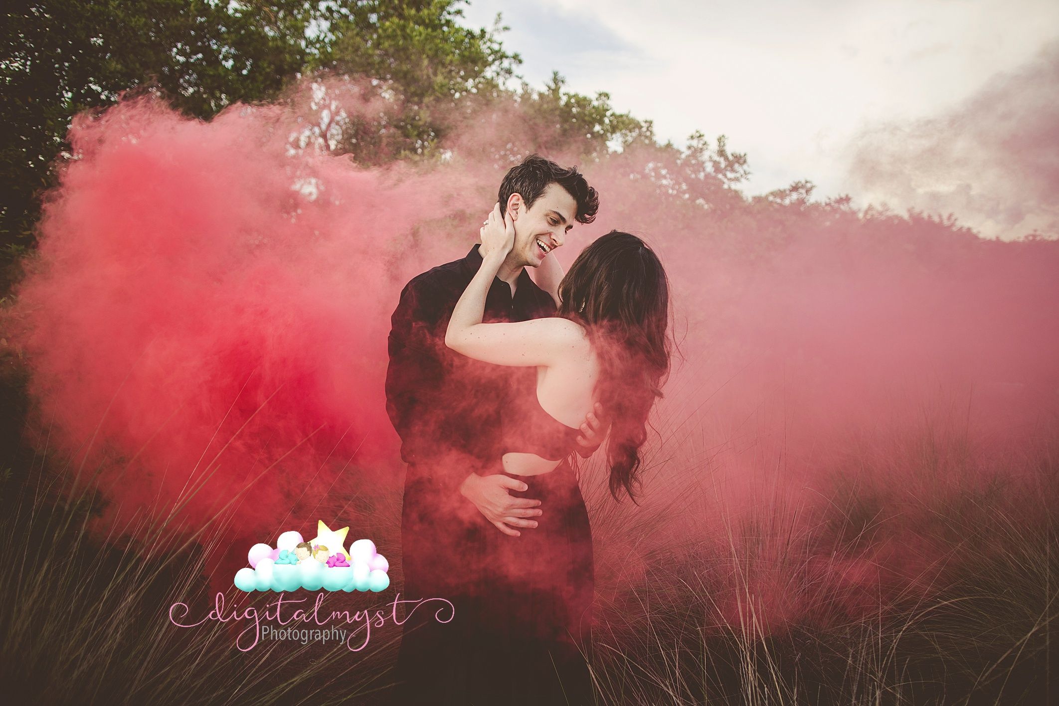 Couple standing in a dramatic red smoke cloud during sunset photo shoot at the beach.