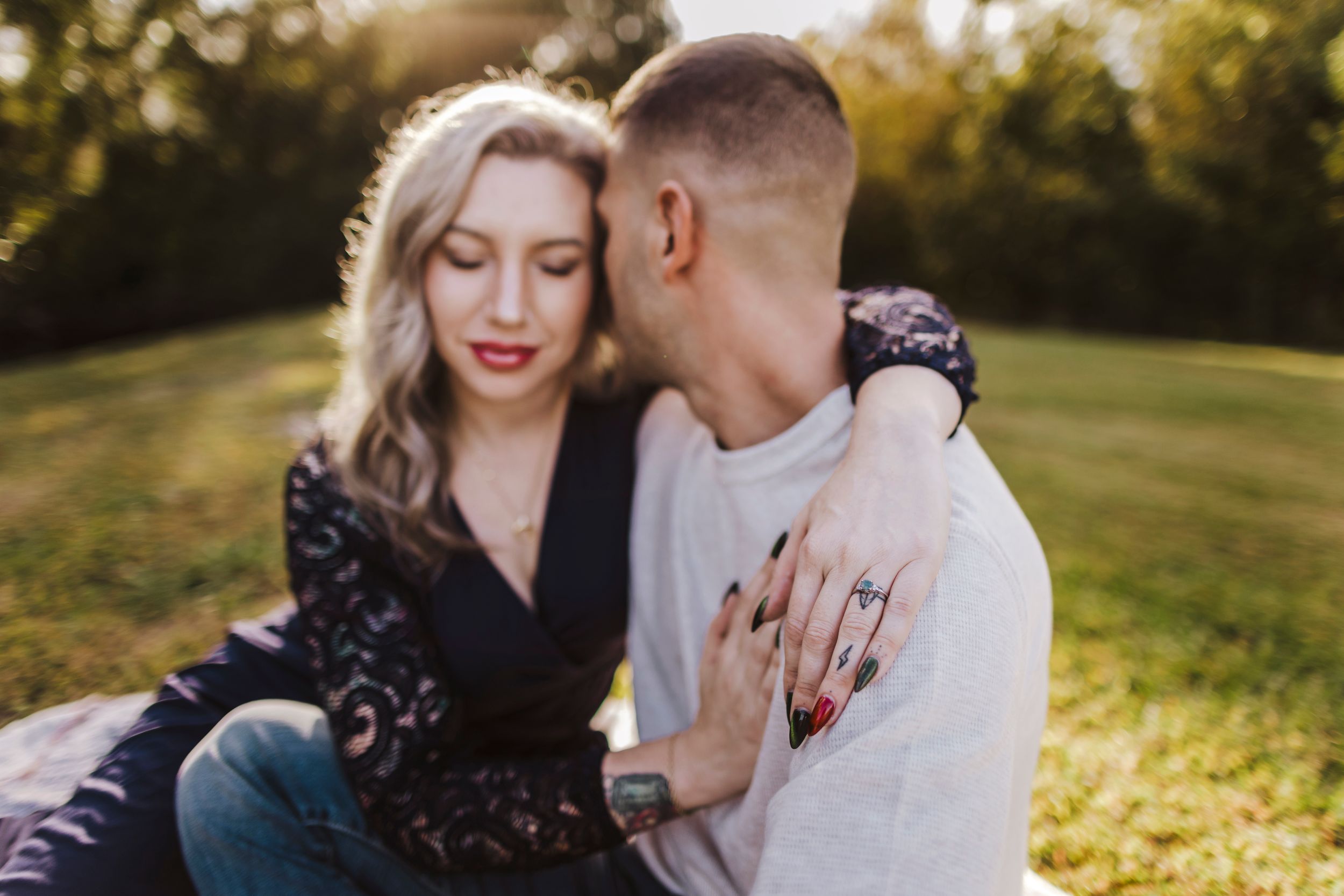 A couple shares an intimate moment in a sunlit field.