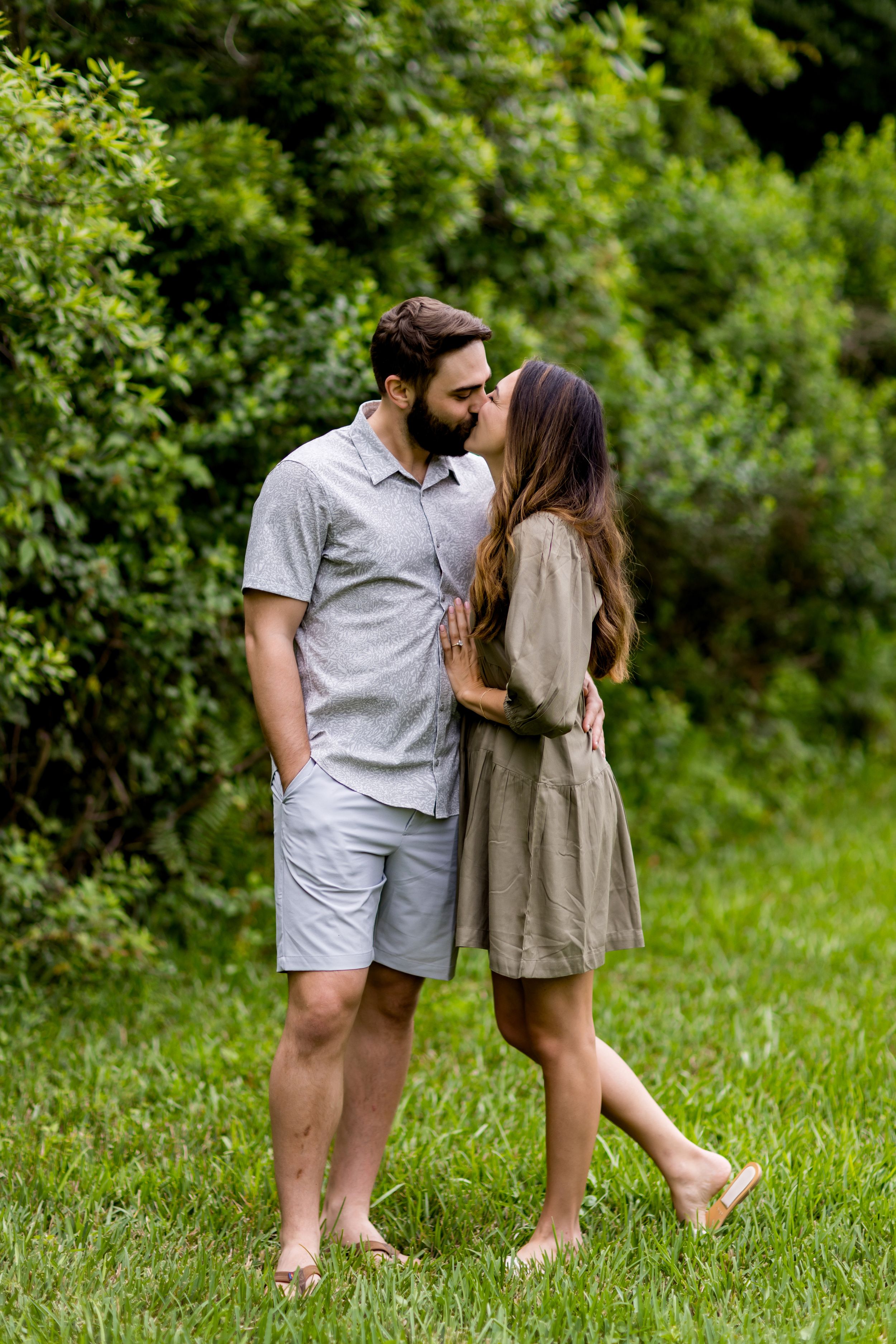 A couple shares a romantic moment while standing barefoot in grass.
