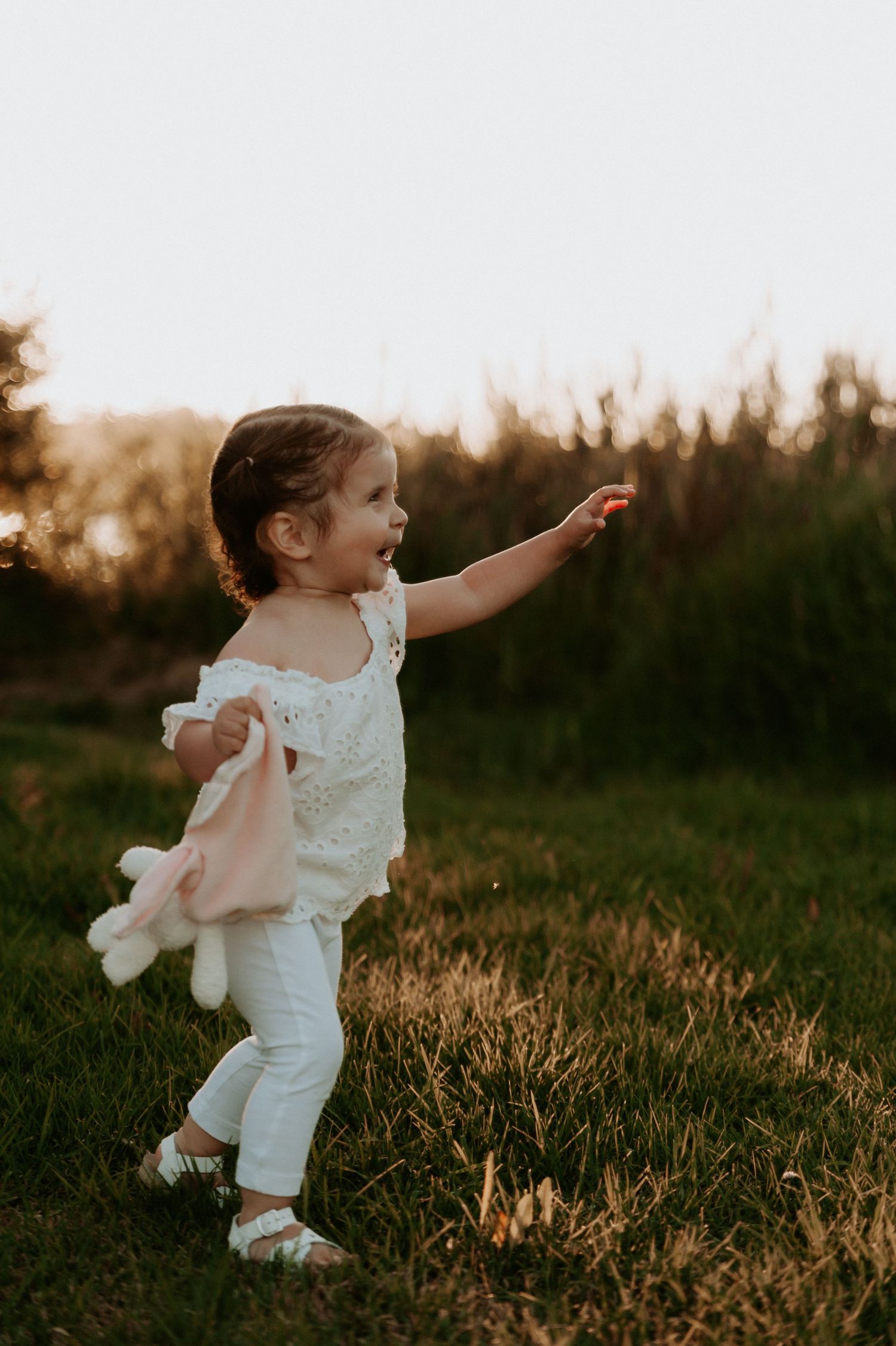 A child in white outfit runs playfully through a grassy field at sunset.
Altona Family Photographer Melbourne
