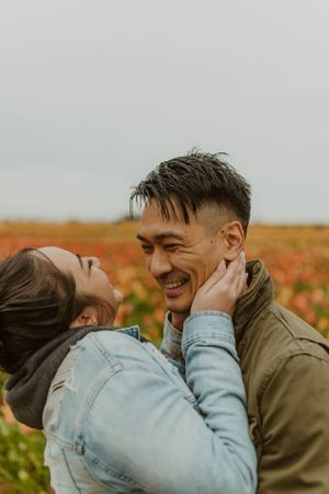 Couple sharing intimate moments in a colorful flower field at sunset.