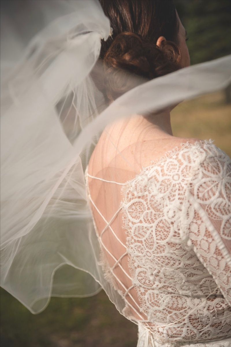 close up of bride's shoulder in her wedding dress with veil floating in the wind