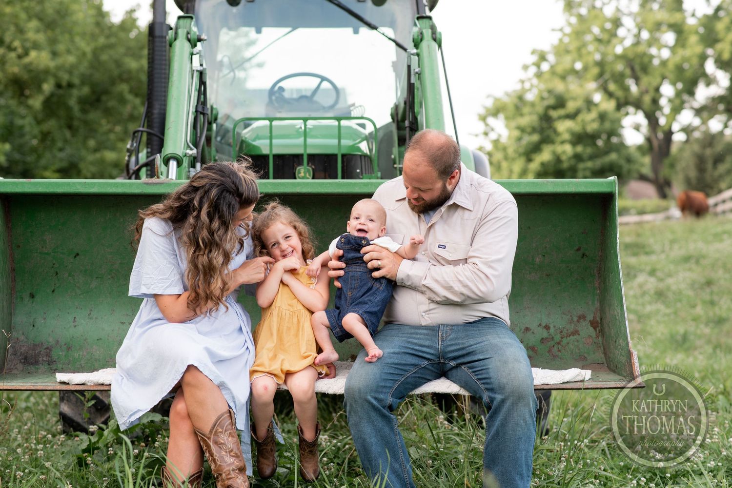 Family sharing a joyful moment while sitting on a green tractor bucket.