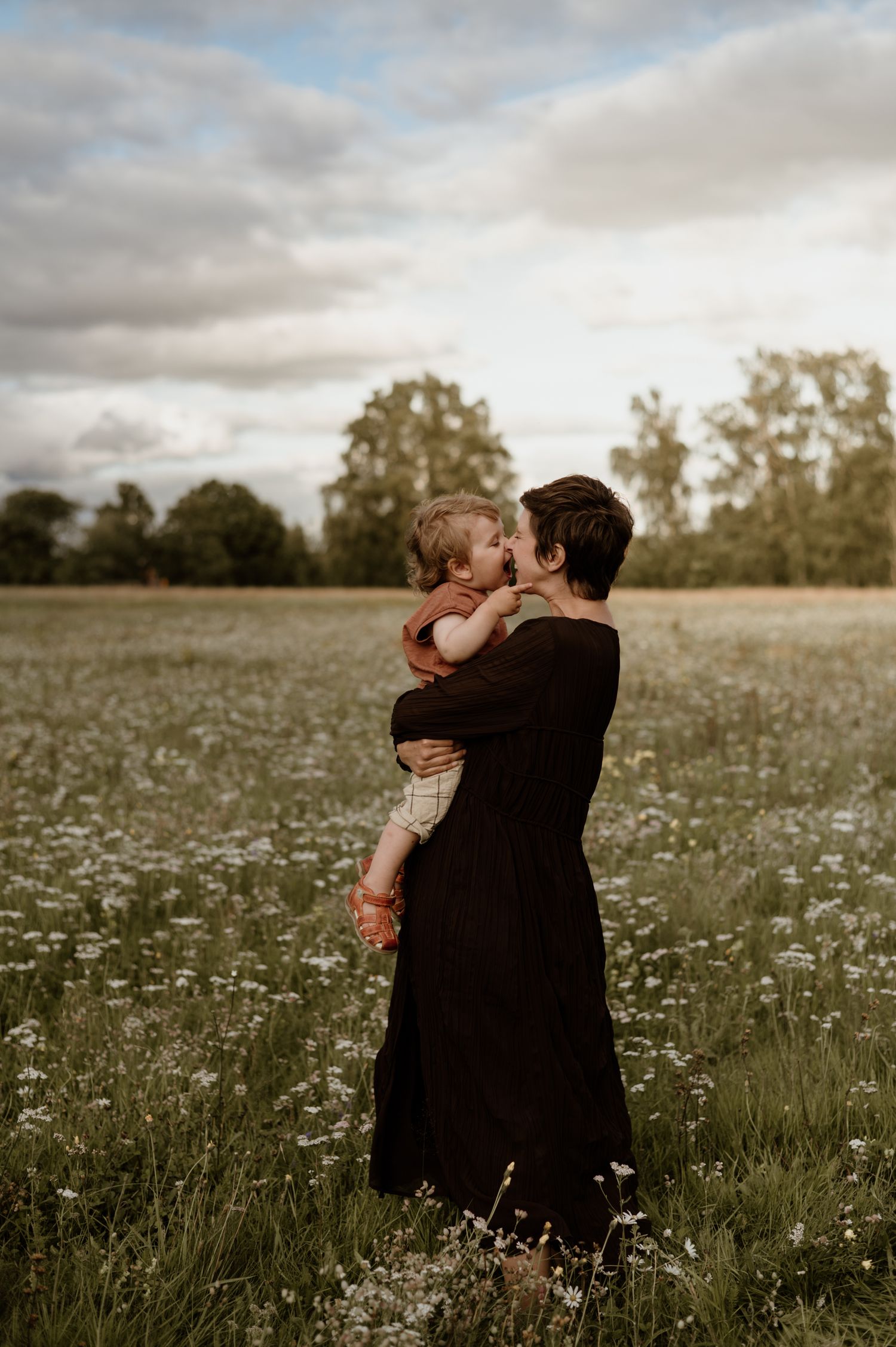 Mamma och son kramas på blomsteräng.