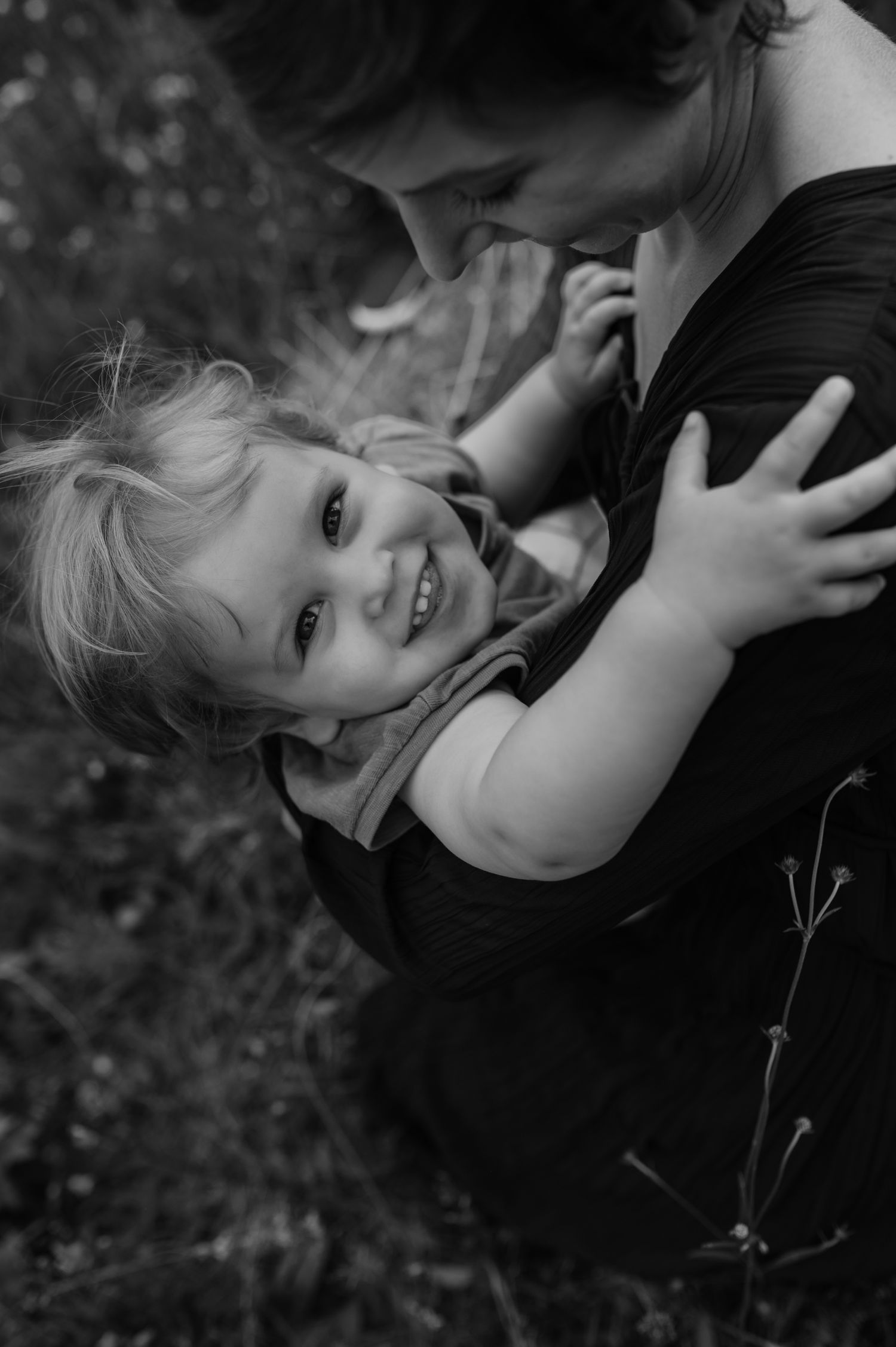 Liten pojke i sin mammas famn. Svartvit bild.