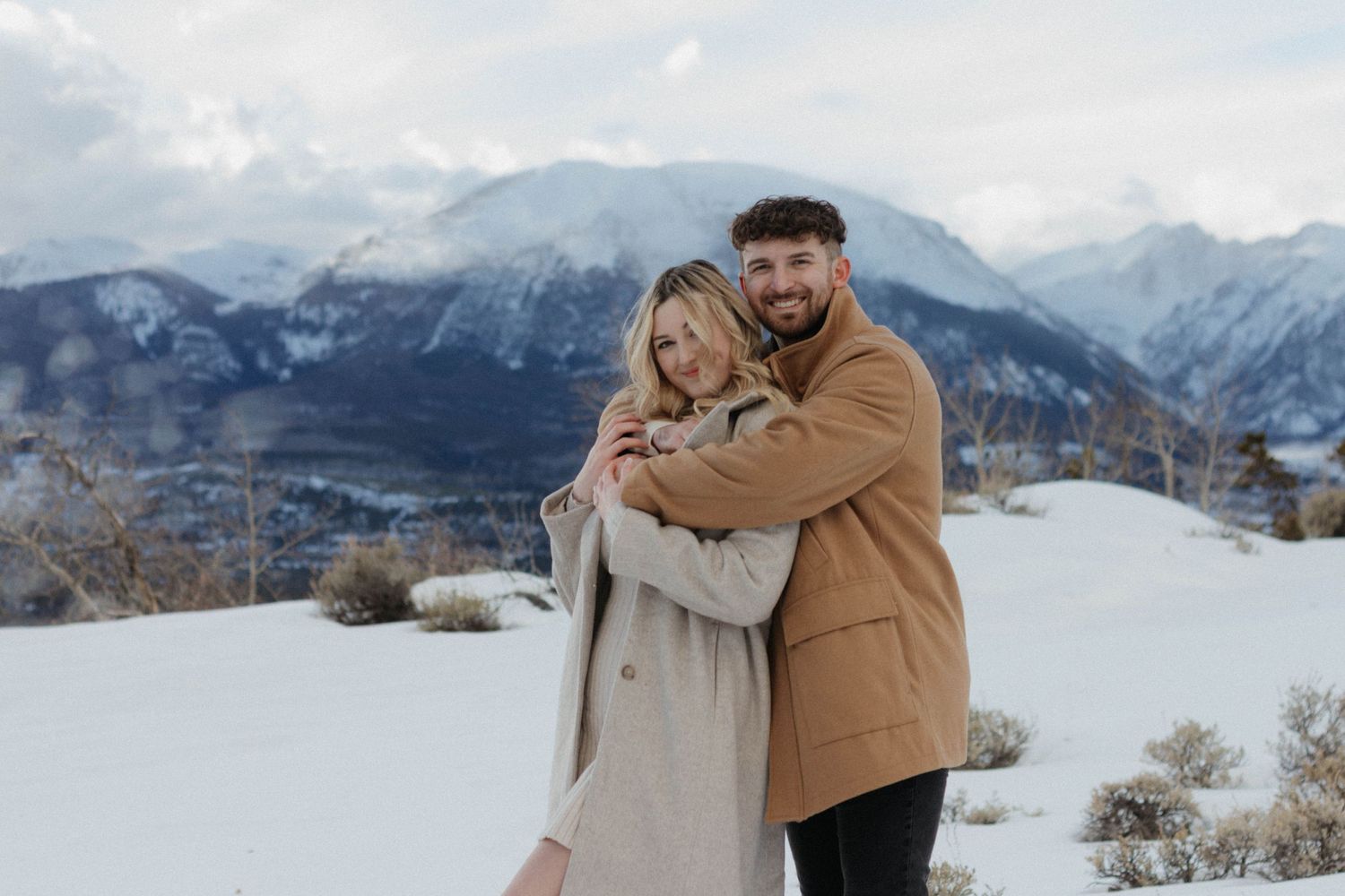 Engagement photoshoot in Breckenridge Colorado. Couple wearing winter clothes, whit snow mountains on the background.