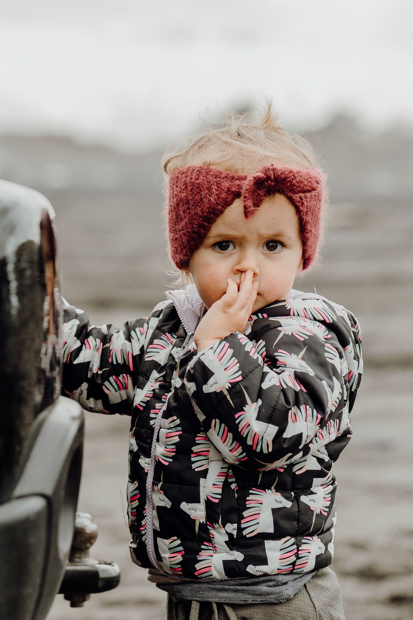 A unicorn jacket and a headband on a windy and overcast day at Muriwai Beach.