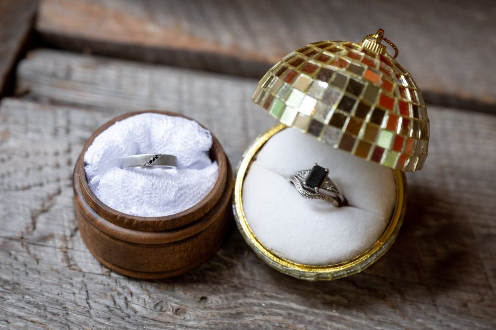 Wedding rings displayed artistically on rustic wooden surface with golden decorative boxes.