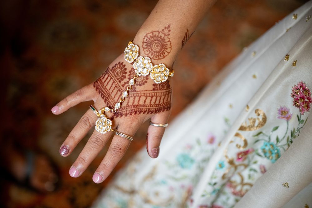 Intricate henna design adorns a hand decorated with gold jewelry and bangles.