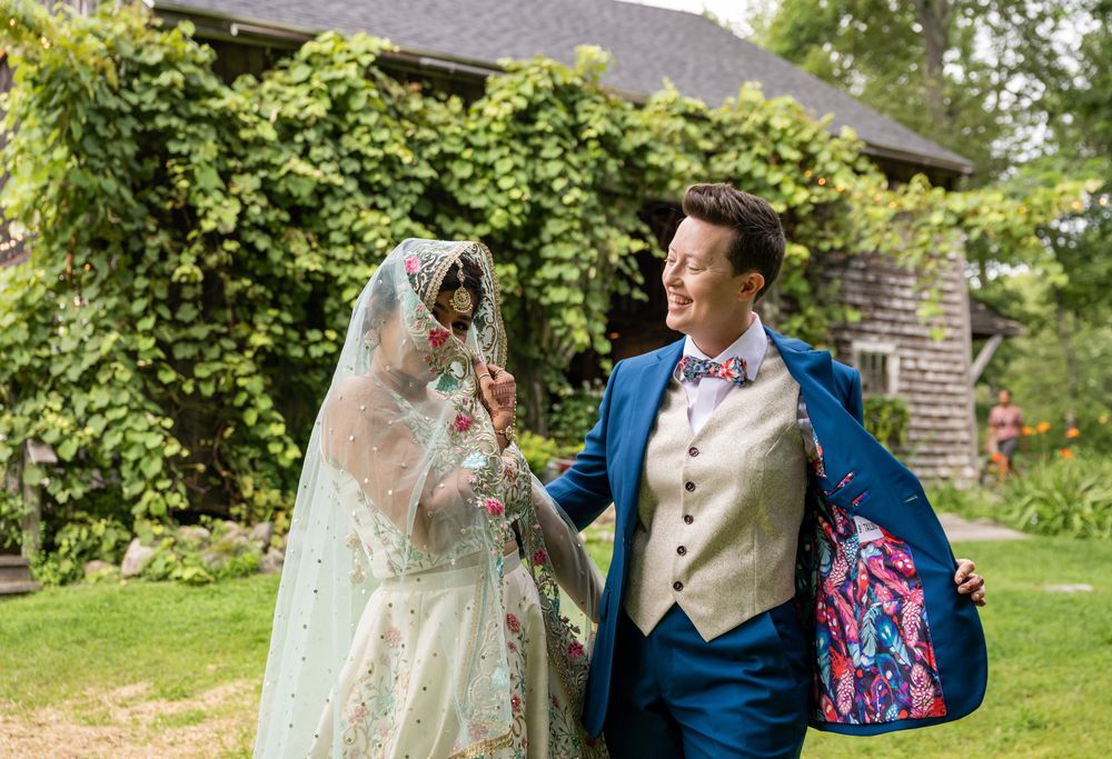 A playful wedding moment captured in a garden setting with ivy-covered walls.