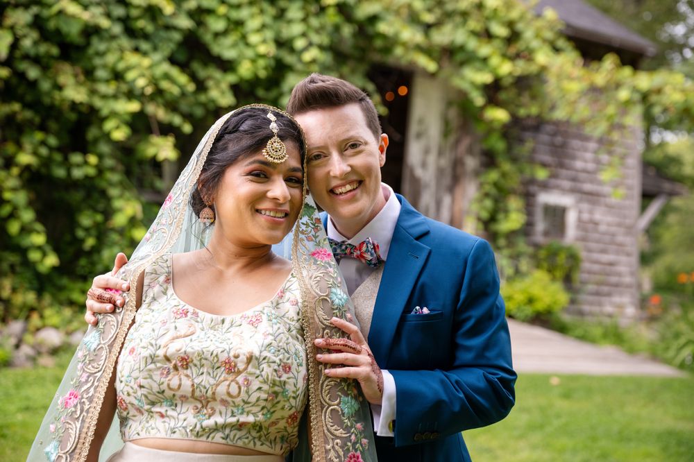 A joyful outdoor wedding portrait captured in a garden setting.