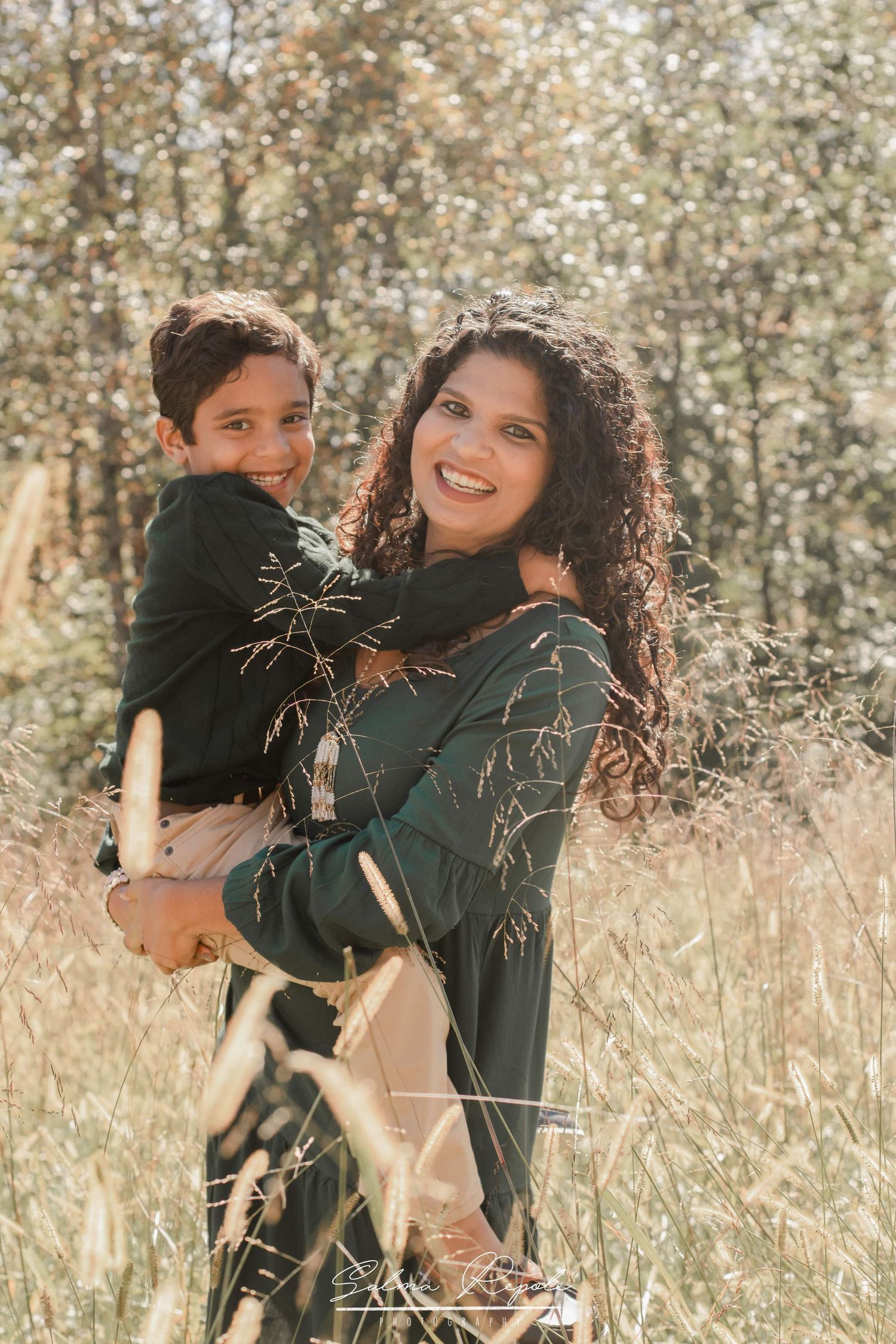 Candid moments captured in tall grass during golden hour family photoshoot.